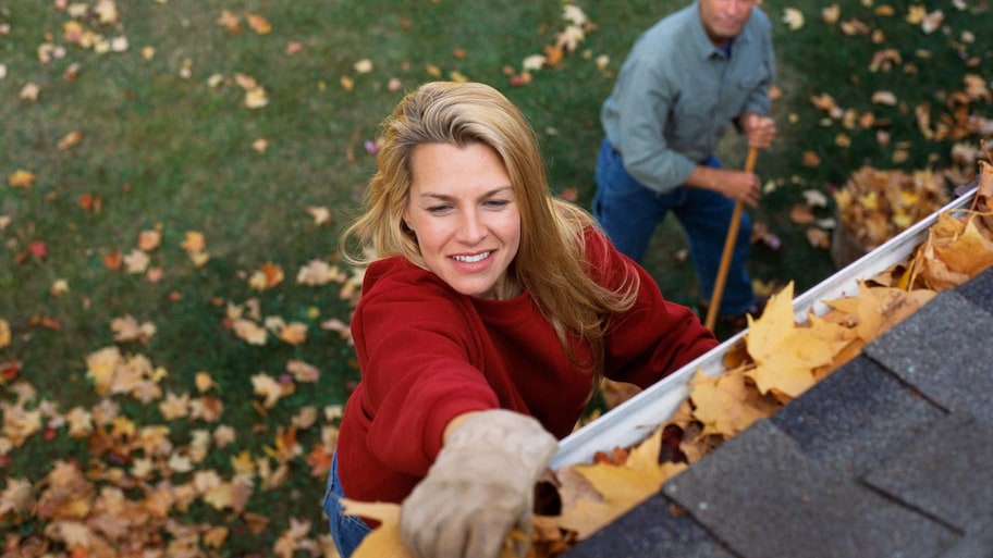 Couple removing leaves out of gutters