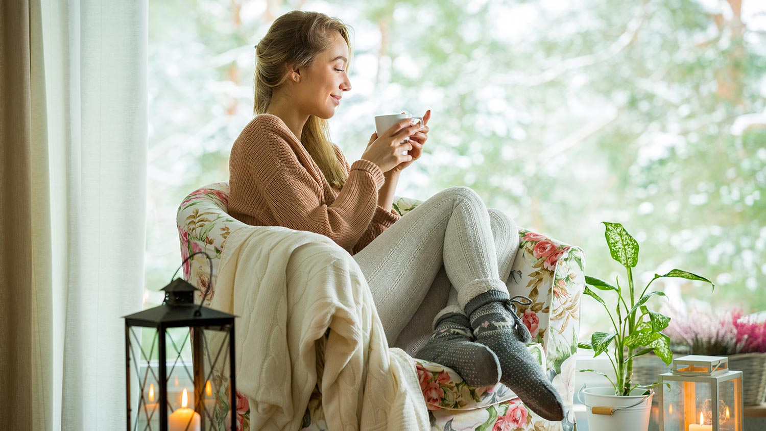 Woman with coffee and blanket in cozy room