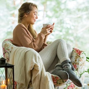 Woman with coffee and blanket in cozy room