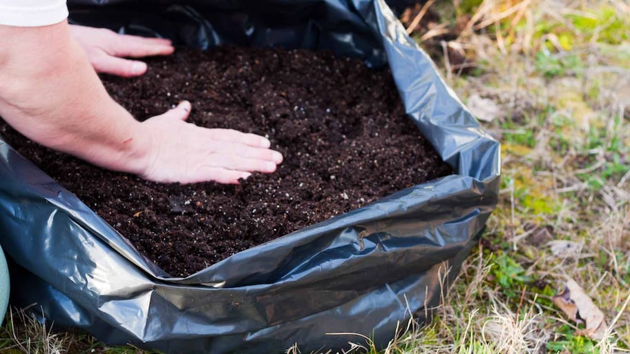 man putting dirt in a bag to recycle 