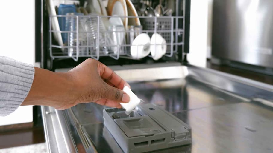 Woman placing dishwasher detergent pod into dispenser