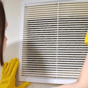 woman replacing dusty air vent 