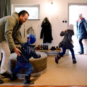 A family putting their coats on in house’s mudroom