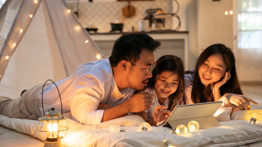 A family of three using a tablet in their home at night