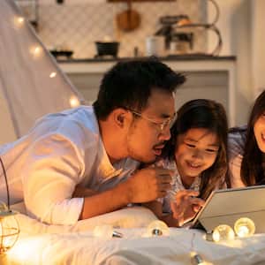 A family of three using a tablet in their home at night