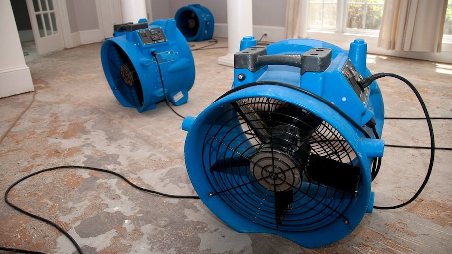 Large fans work to dry subfloor after flood