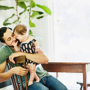 A father holding his daughter sitting at the wooden dining table