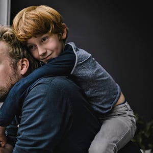  father and son looking out the window on a rainy day 