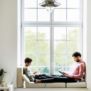 A father and son sitting by the window reading their books