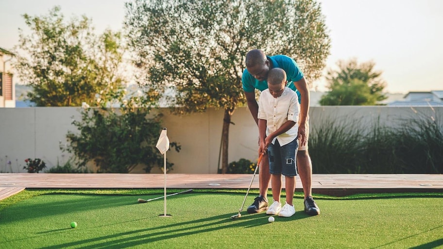 A father teaching his son golf in their backyard