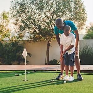 A father teaching his son golf in their backyard