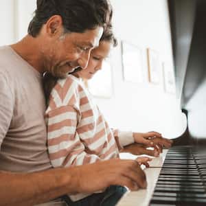 Father and daughter playing the piano.
