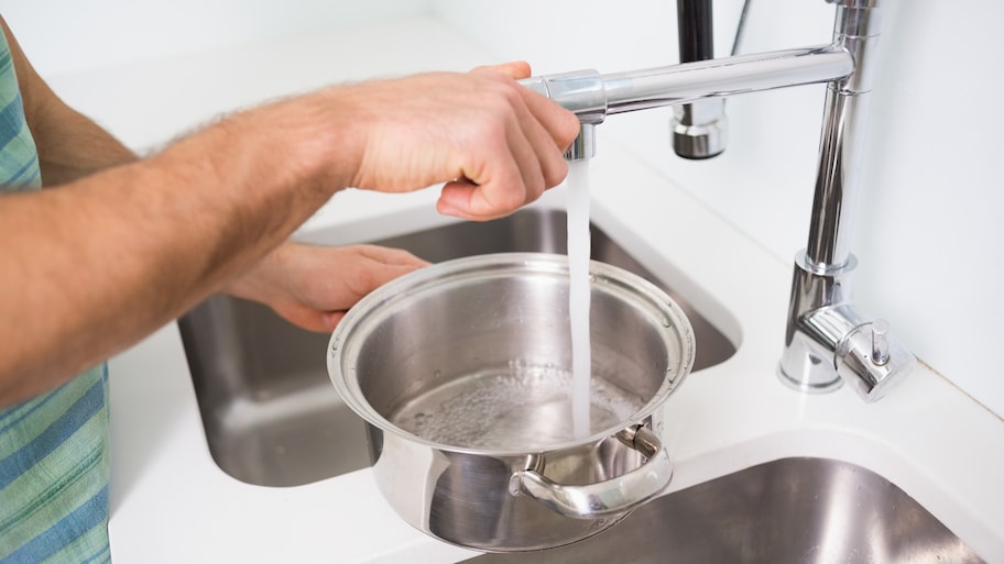 Filling pan with water at kitchen sink