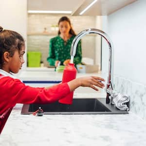 Girl using kitchen faucet to fill up a water bottle