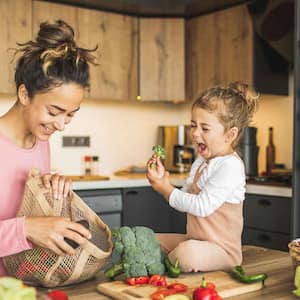 Daughter helping mom prep vegetables in the kitchen