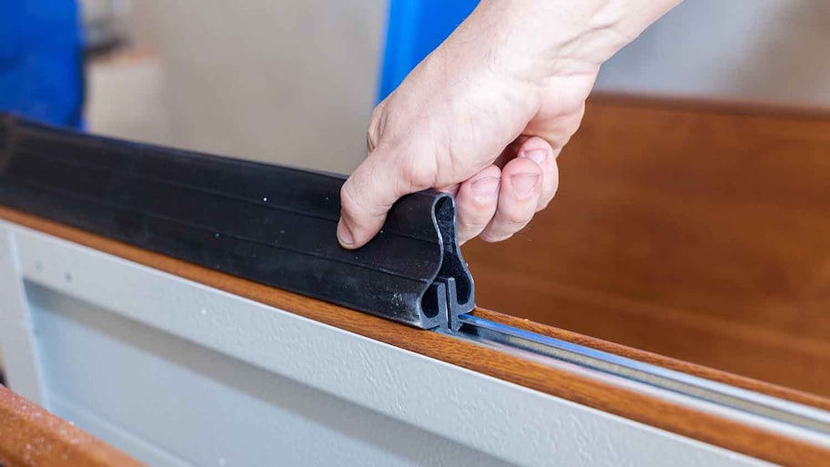 Technician installing garage door weather stripping