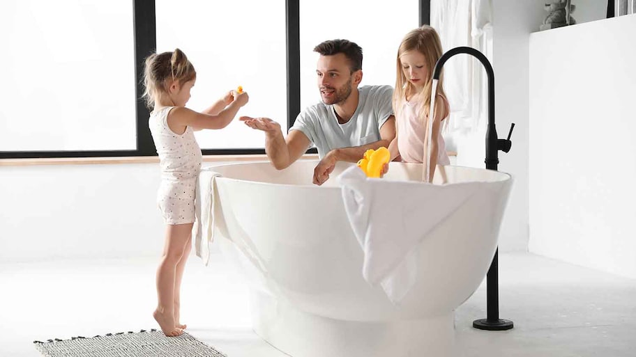 Father and daughters filling bathtub with water