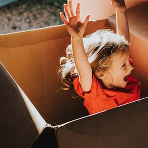 A little girl jumping inside a huge cardboard box