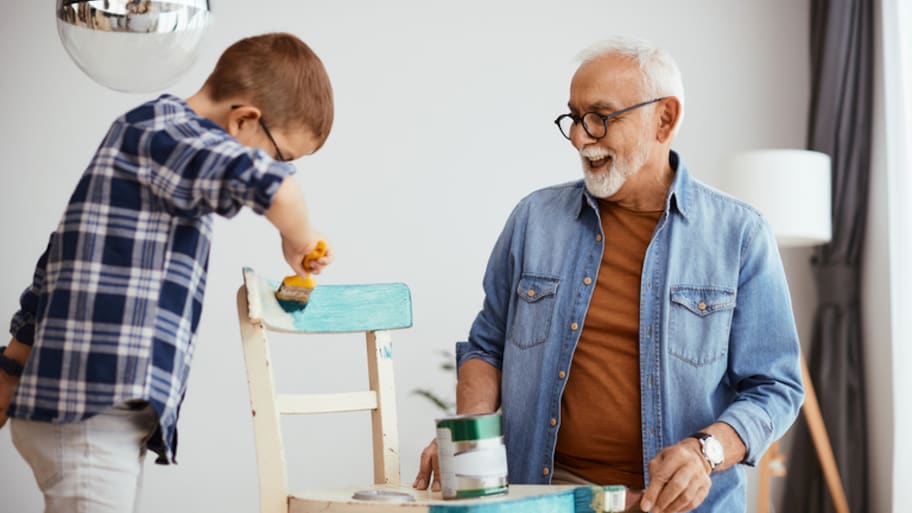 Grandfather and grandson painting a chair blue