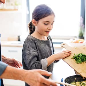 Senior grandfather and granddaughter preparing food indoors in kitchen