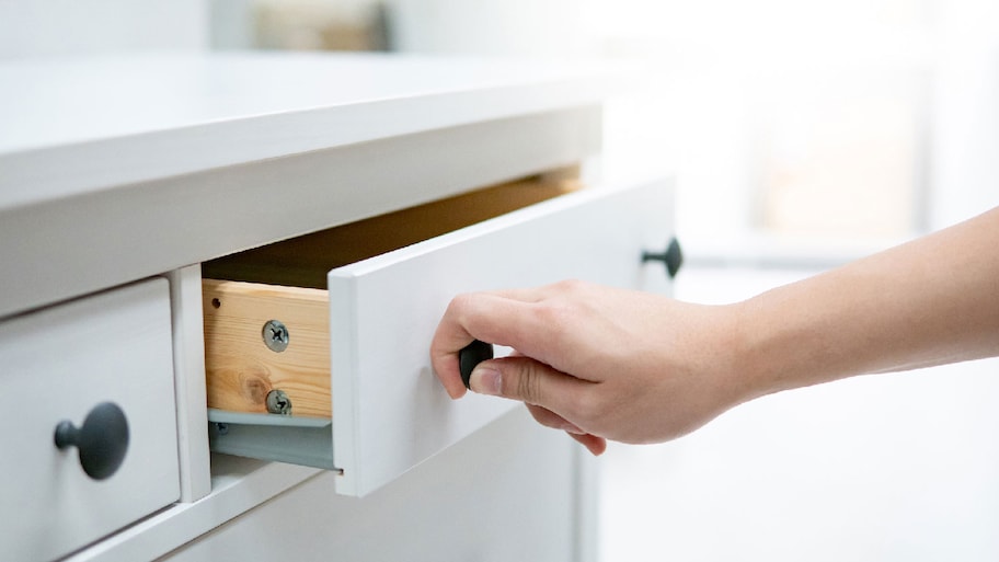 Close-up of a hand opening a cabinet drawer