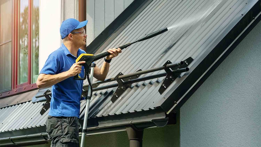 handyman on ladder cleaning roof