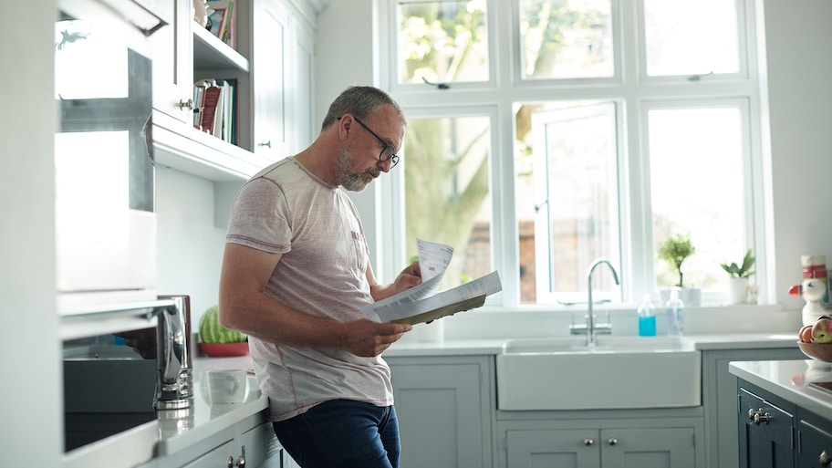 Man reviewing paperwork in kitchen