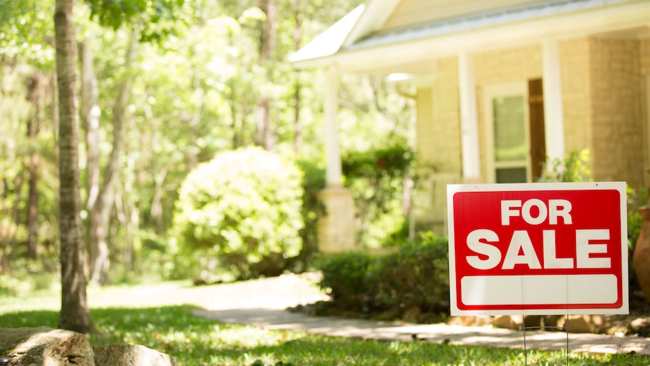 A home for sale with a real estate sign in front of it