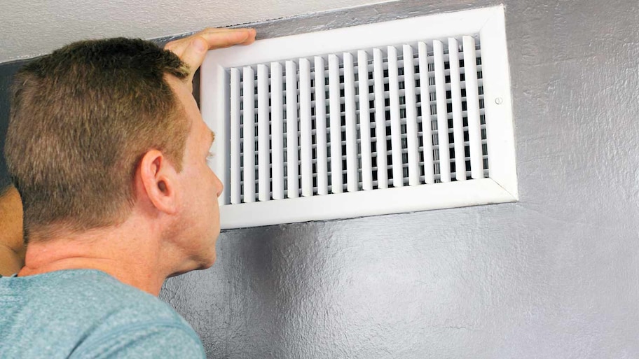 man inspecting home air vent