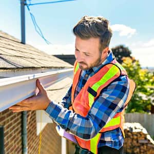 An inspector examining a house’s gutters