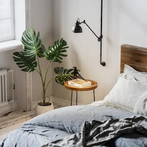 The interior of a bedroom with a potted plant, a night table and a heater