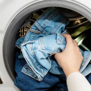 person putting jeans in dryer machine