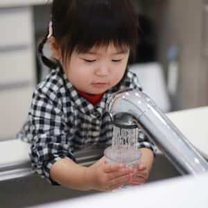 A kid filling a glass with tap water