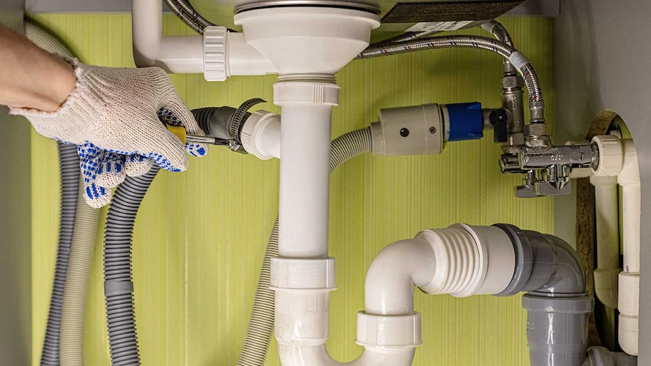 Worker tightens dishwasher drain hose