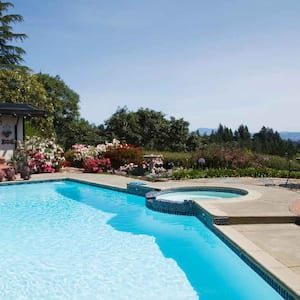 A large pool with a hot tub build next to it