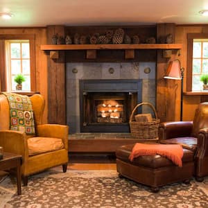 A library in a house with two armchairs and a fireplace with a hearth