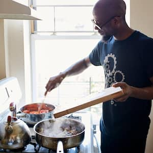 : Man holding cutting board cooking on stove