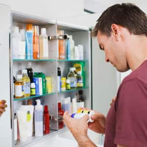 A man looking at bottles in a medicine cabinet