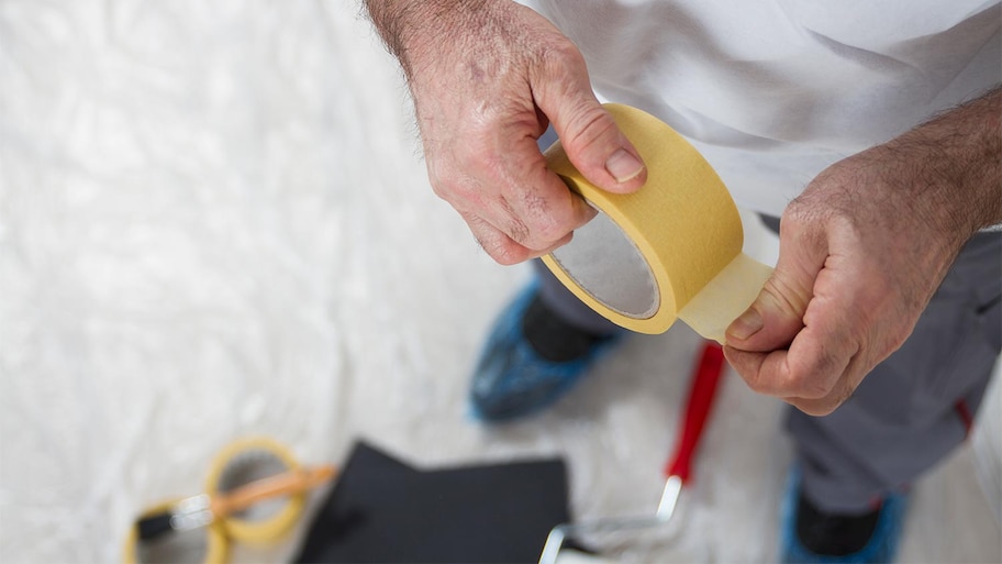 man preparing walls with masking tape 