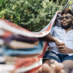 A man napping on a hammock in a back yard