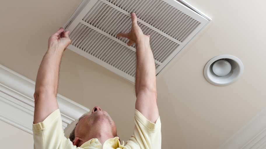 A senior man placing back an air duct