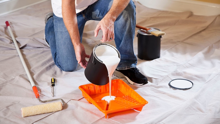 man pouring paint into a tray