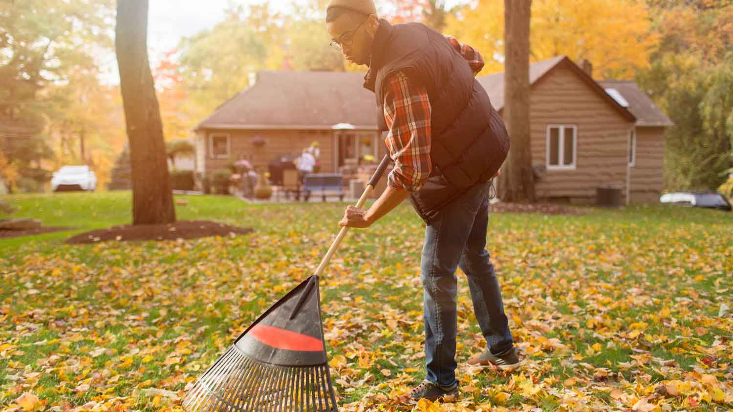 A man raking his yard during fall