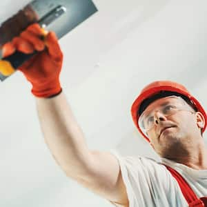 A man skim coating a wall