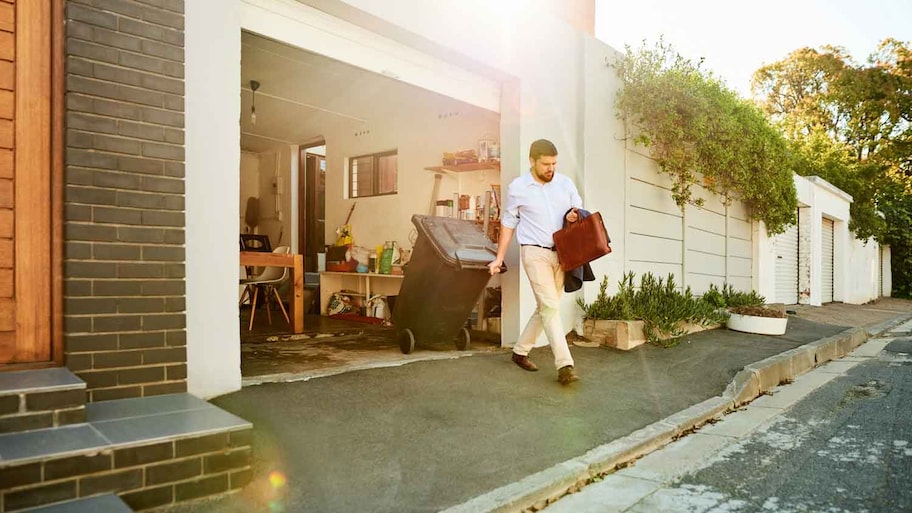 A man taking the trash out of the garage