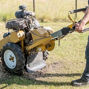 Man using tree stump grinder in his yard