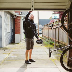 Male commuter with backpack closing garage door