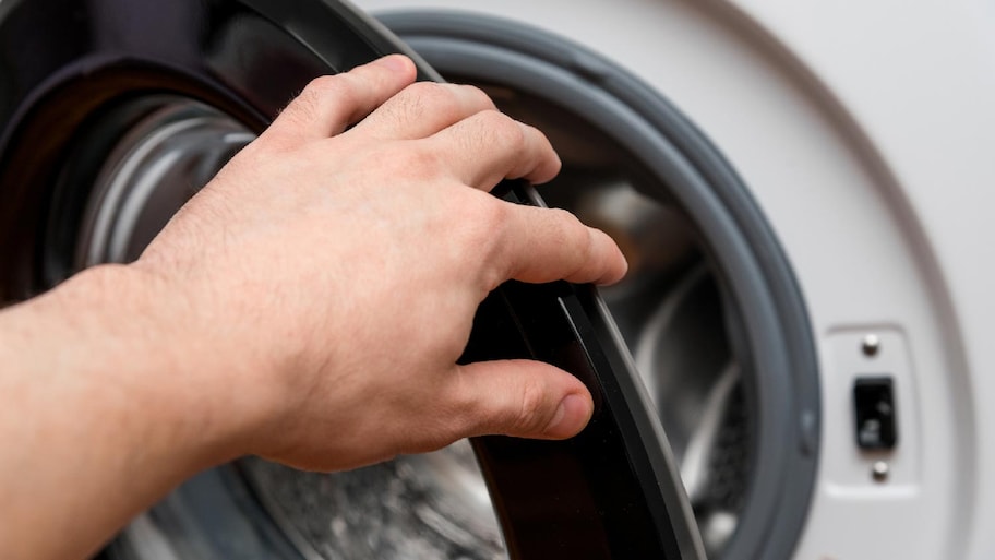 A man’s hand opening the washing machine door