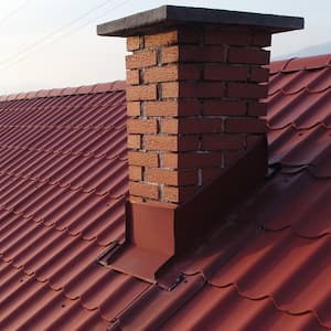 A metal roof of a house with a brick chimney