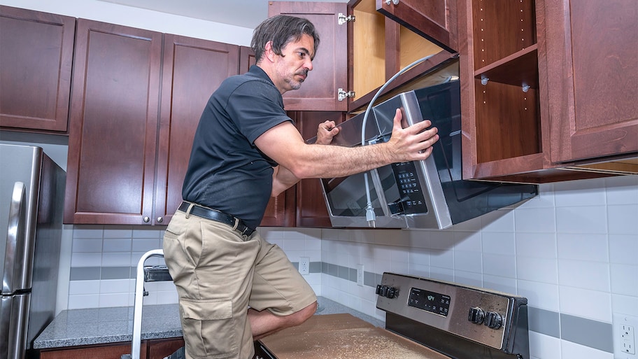 A man installs a microwave over a stove